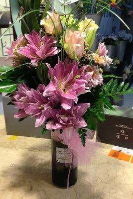 Ανθοπωλείο . Μπουκέτο με άνθη εποχής σε  γυάλινο βάζο με στρώσεις χρωματιστής διακοσμητικής άμμου