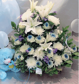 Flower arrangement in basket with balloons and teddy bear.