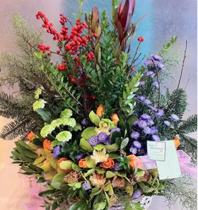 Flower arrangement in basket with season flowers and relative greens