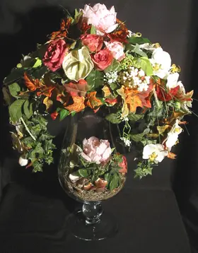 Artificial flower arrangement in big champagne glass