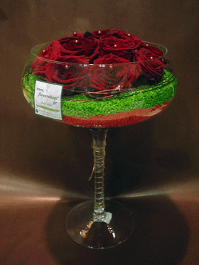Red roses in glass vase with decorative colored pebbles layers