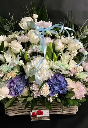 Flower arrangement in basket with balloons and teddy bear.