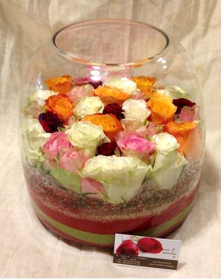 Arrangement of multi colored roses  in vase with decorative colored sand layers!!!