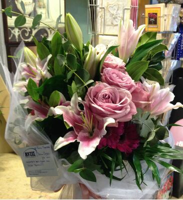 Ανθοπωλείο . Μπουκέτο με άνθη εποχής σε  γυάλινο βάζο με στρώσεις χρωματιστής διακοσμητικής άμμου