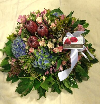 Condolences arrangement with exclusive tropical and seasonal flowers