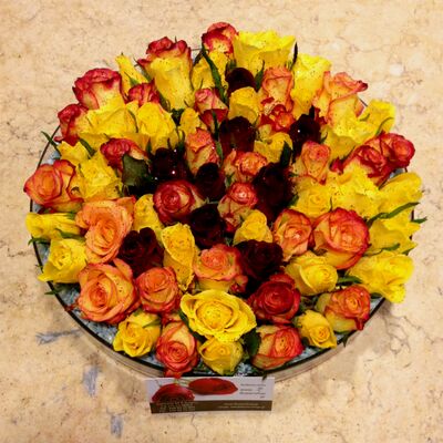 Mixed colored roses in glass with colored sand decoration