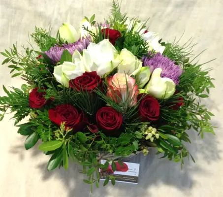 Flower arrangement in basket with season flowers and relative greens
